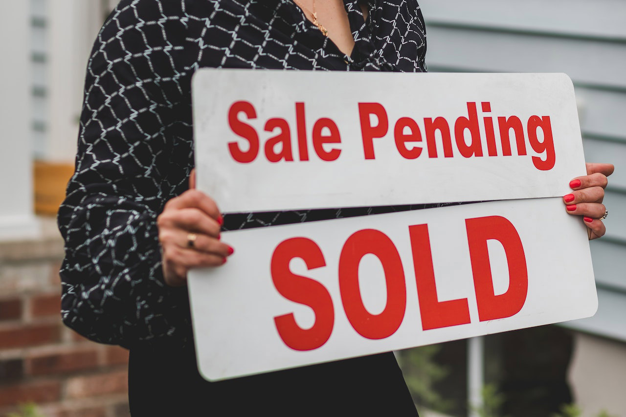 A Young Family Holds a Sold Sign as First Time Homebuyers